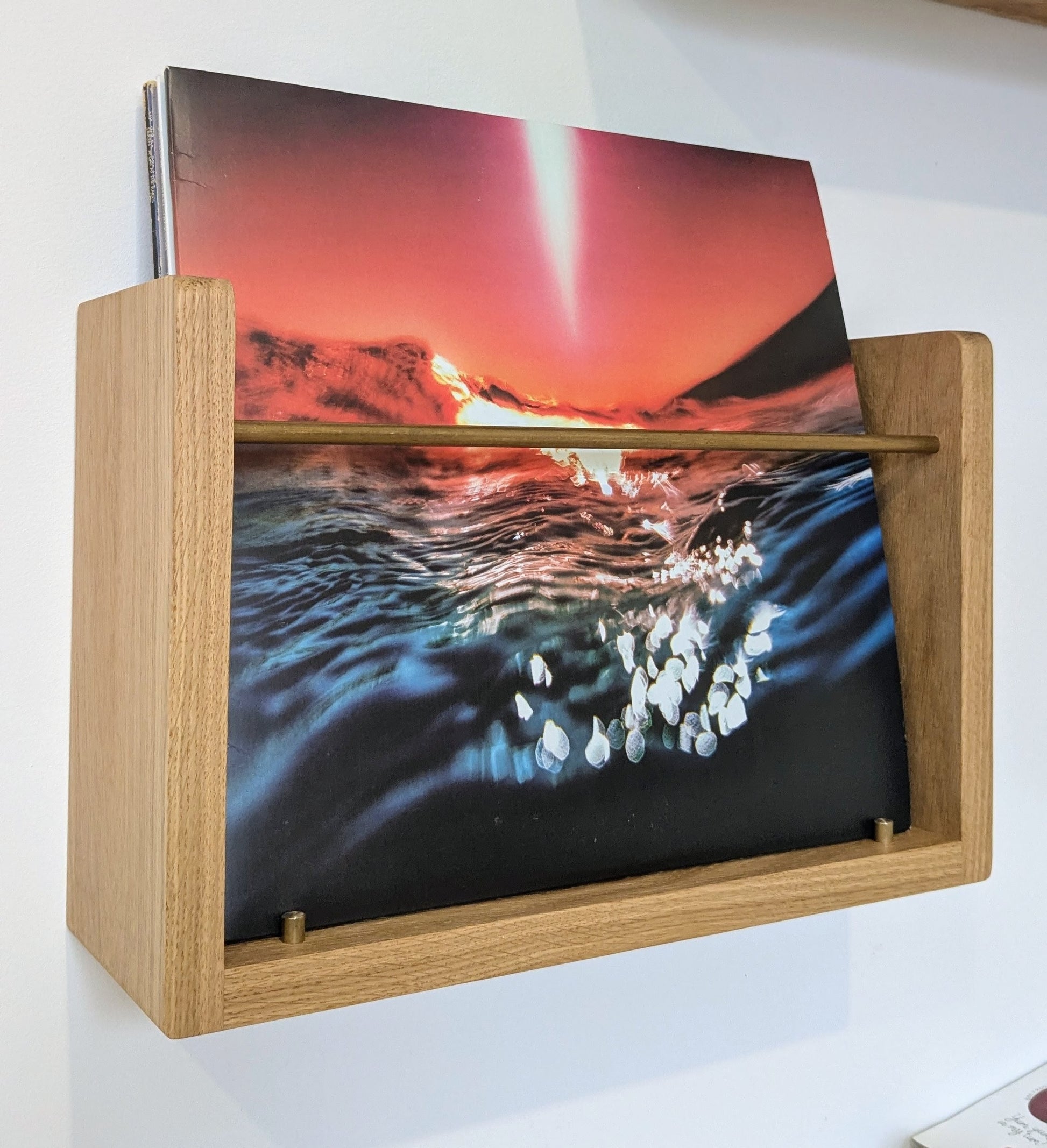 Wooden album holder with a vinyl record featuring a sunset over water design.