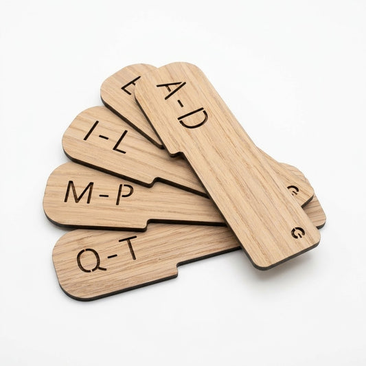 Four wooden letter spacing cards with engraved uppercase letters (E-A-D, I-L, M-P, Q-T) fanned out on a clean white background.